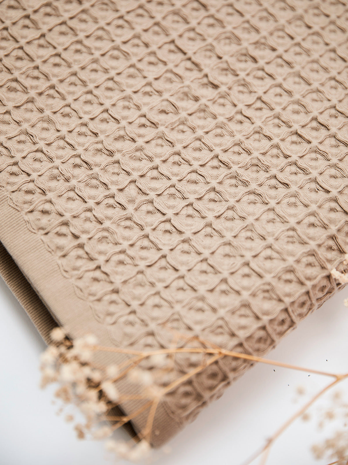 Light grey waffle cotton throw or beach towel, showcasing a textured weave, perfect for adding a touch of elegance to your home or beach outings. Made from high-quality cotton, this versatile piece offers both style and comfort.