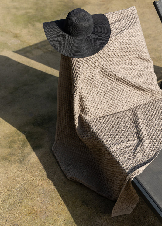 Light grey waffle cotton throw or beach towel, showcasing a textured weave, perfect for adding a touch of elegance to your home or beach outings. Made from high-quality cotton, this versatile piece offers both style and comfort.