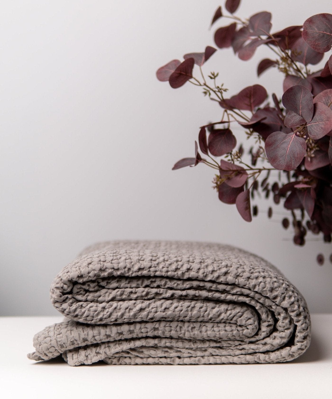 Bloom organic cotton throw in grey with honeycomb pattern, crafted from 100% cotton. Elegant and soft, this versatile bedspread adds a touch of serene style to any space, perfect for cozying up or enhancing home decor.