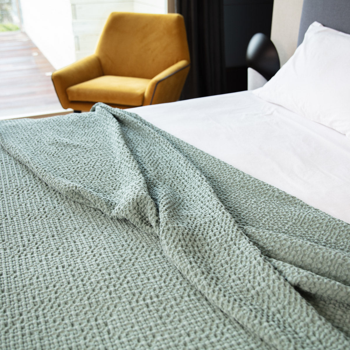 Bloom organic cotton throw in grey with honeycomb pattern, crafted from 100% cotton. Elegant and soft, this versatile bedspread adds a touch of serene style to any space, perfect for cozying up or enhancing home decor.