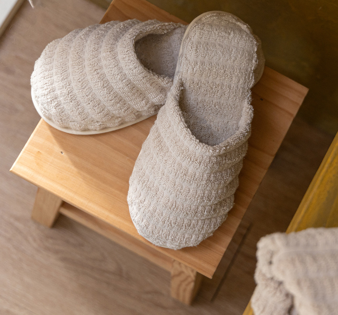 Beige Swell organic cotton bathrobe displayed on a hanger, showcasing its soft texture and elegant design with a tie belt and spacious pockets.